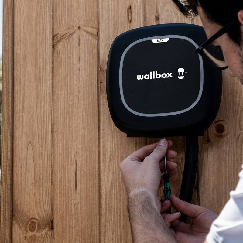 Instalación de un Wallbox Pulsar Max negro sobre una pared de madera.